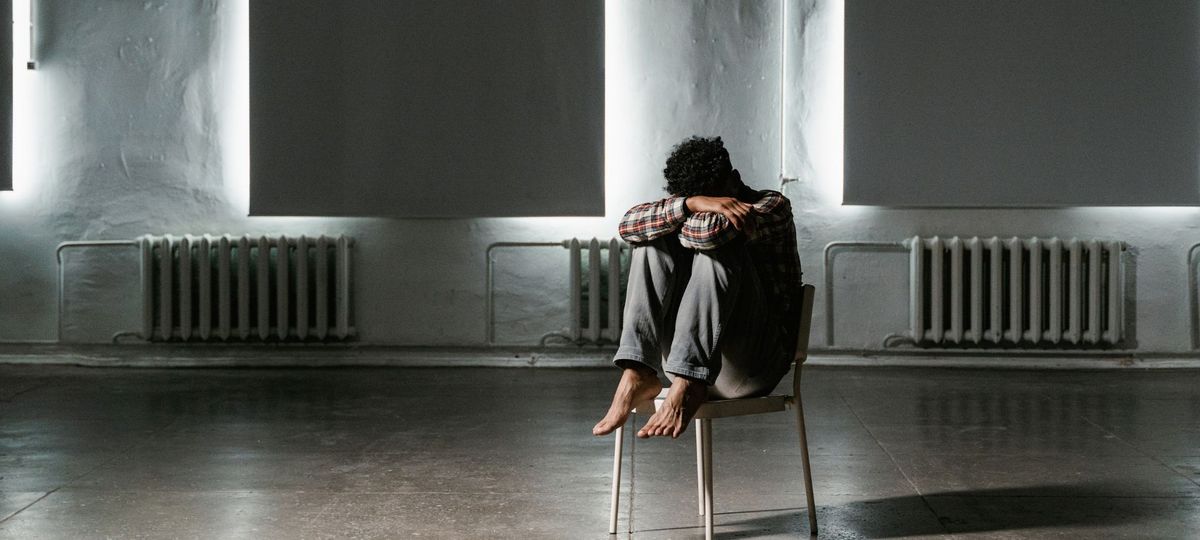 Мужчина сидит в комнате один на стуле